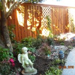 Statue in Garden with Trees, Hanging Planters, Flower Bed